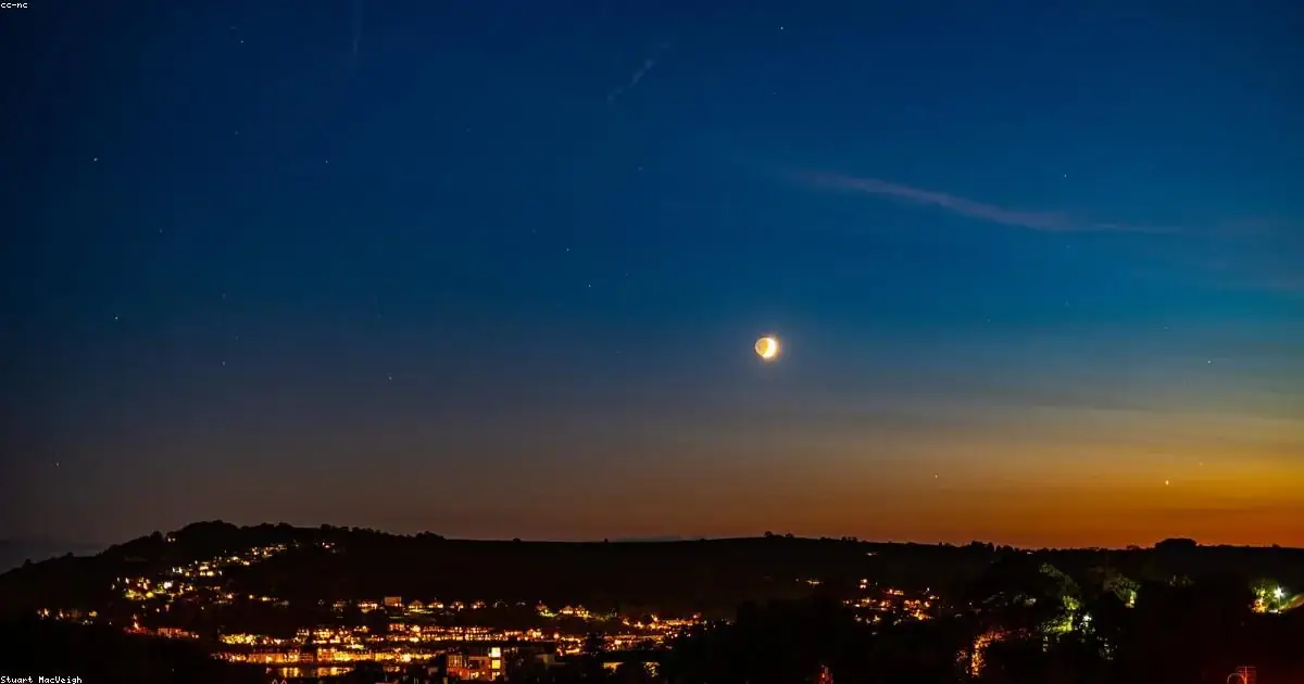 Luna crescente su borgo illuminato al crepuscolo buonanotte natalizia